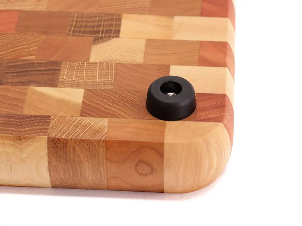 Close-up of an end-grain cutting board corner with a checkered pattern and a black rubber foot, against a white background