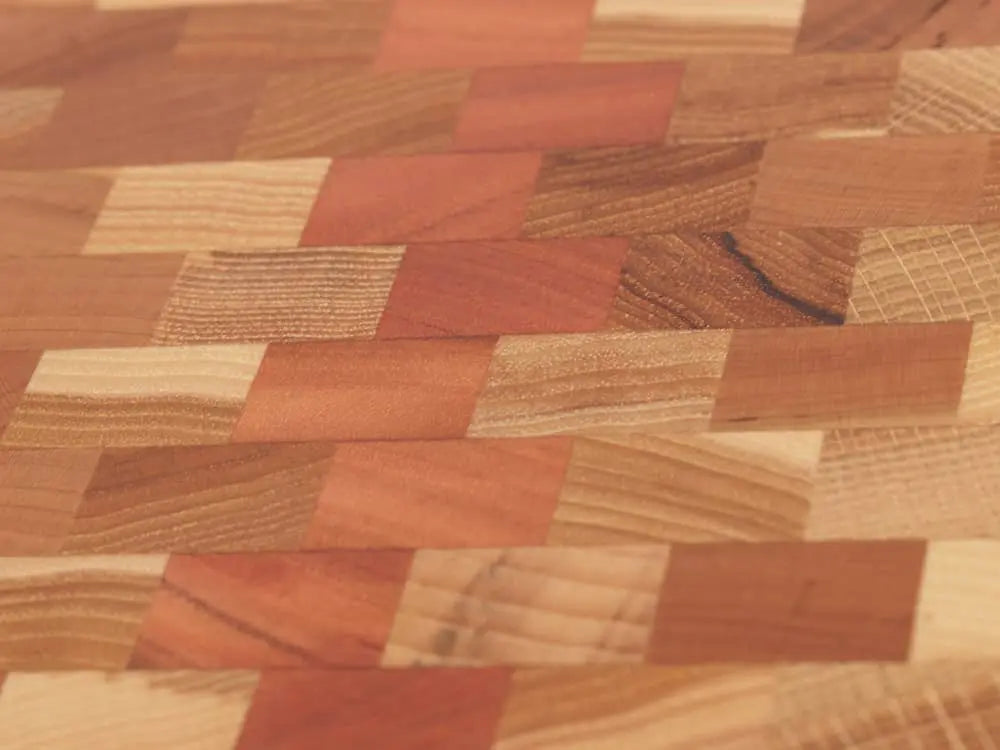 Close-up view of an end-grain cutting board with a checkered pattern of various wood tones, showing the intricate grain and texture
