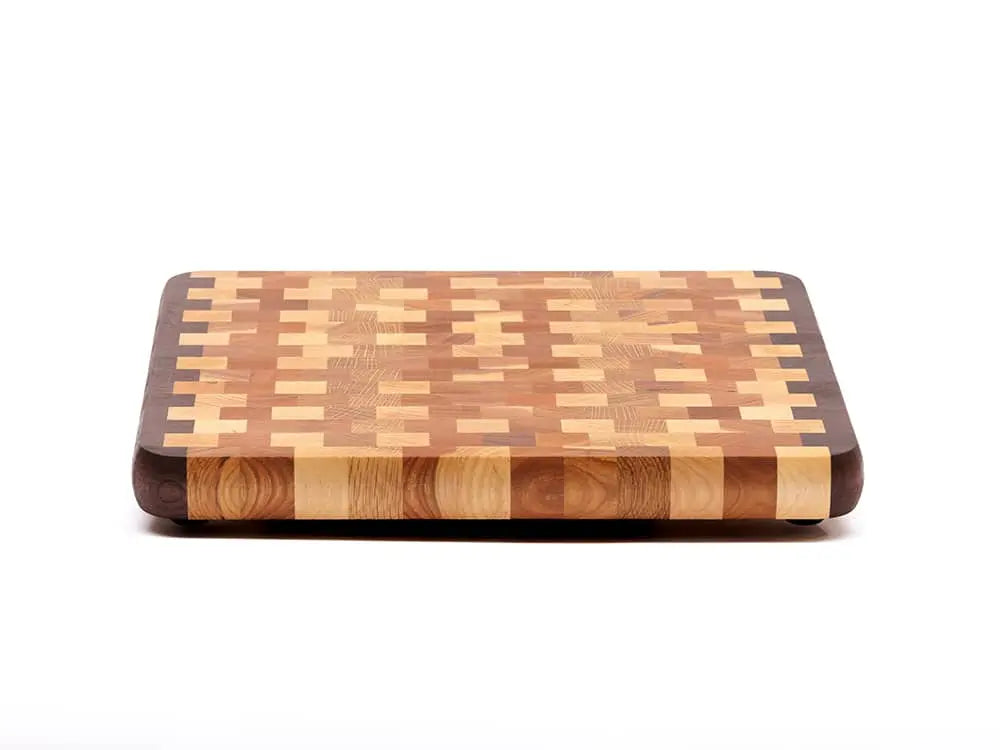 Front view of an end-grain cutting board with a checkered pattern of various wood tones, featuring rounded corners and a smooth finish, against a white background