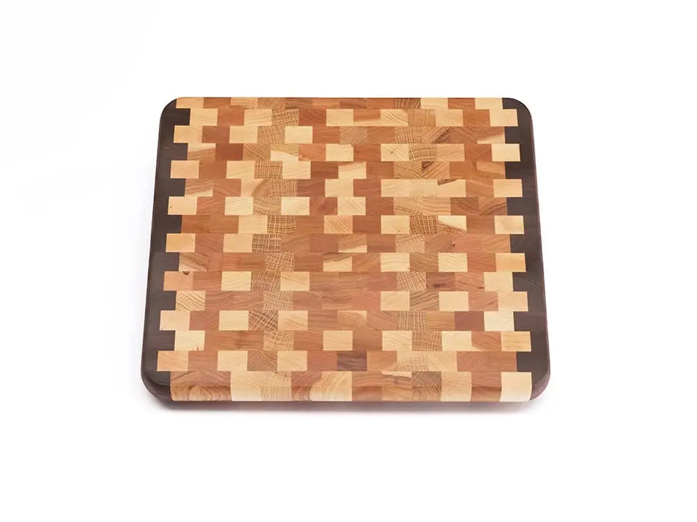 Top view of an end-grain cutting board with a checkered pattern of various wood tones, featuring rounded corners and a smooth finish, against a white background