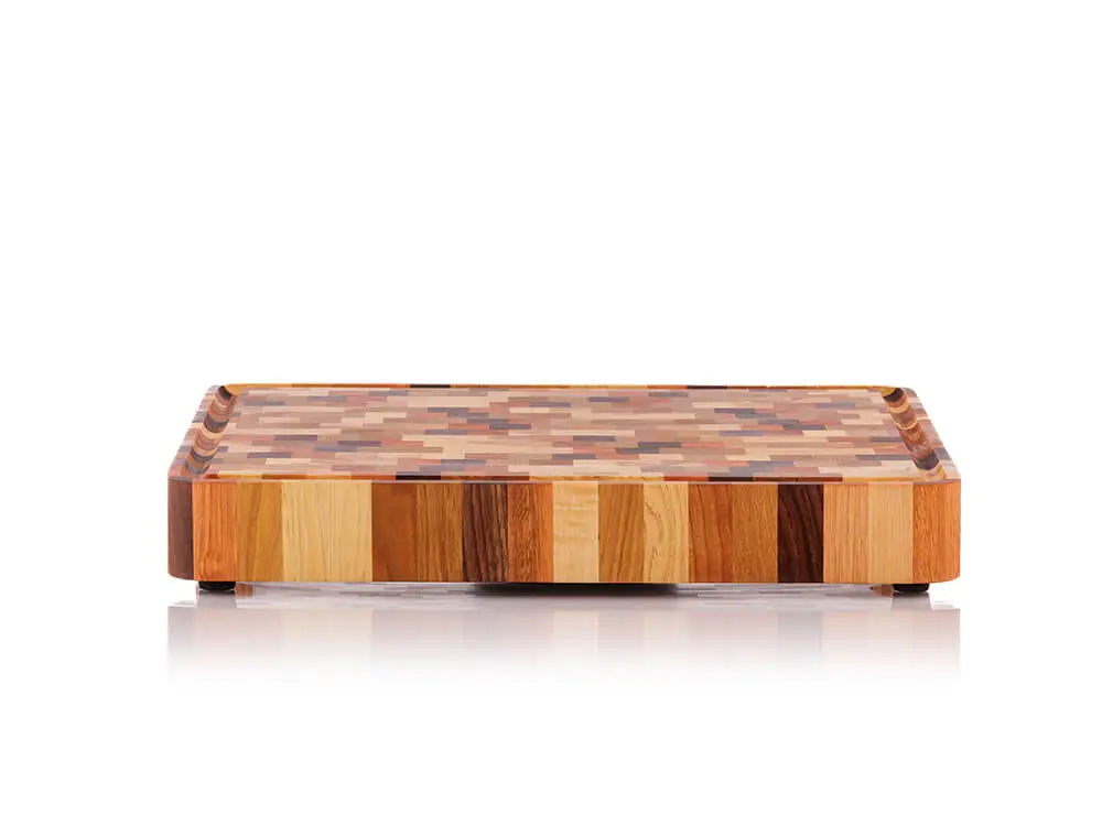 Low front view of an end grain butcher block with a checkered pattern and a juice groove, against a white background