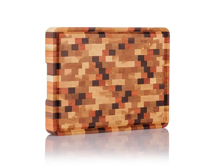 Standing view of an end grain butcher block with a checkered pattern and a juice groove, against a white background