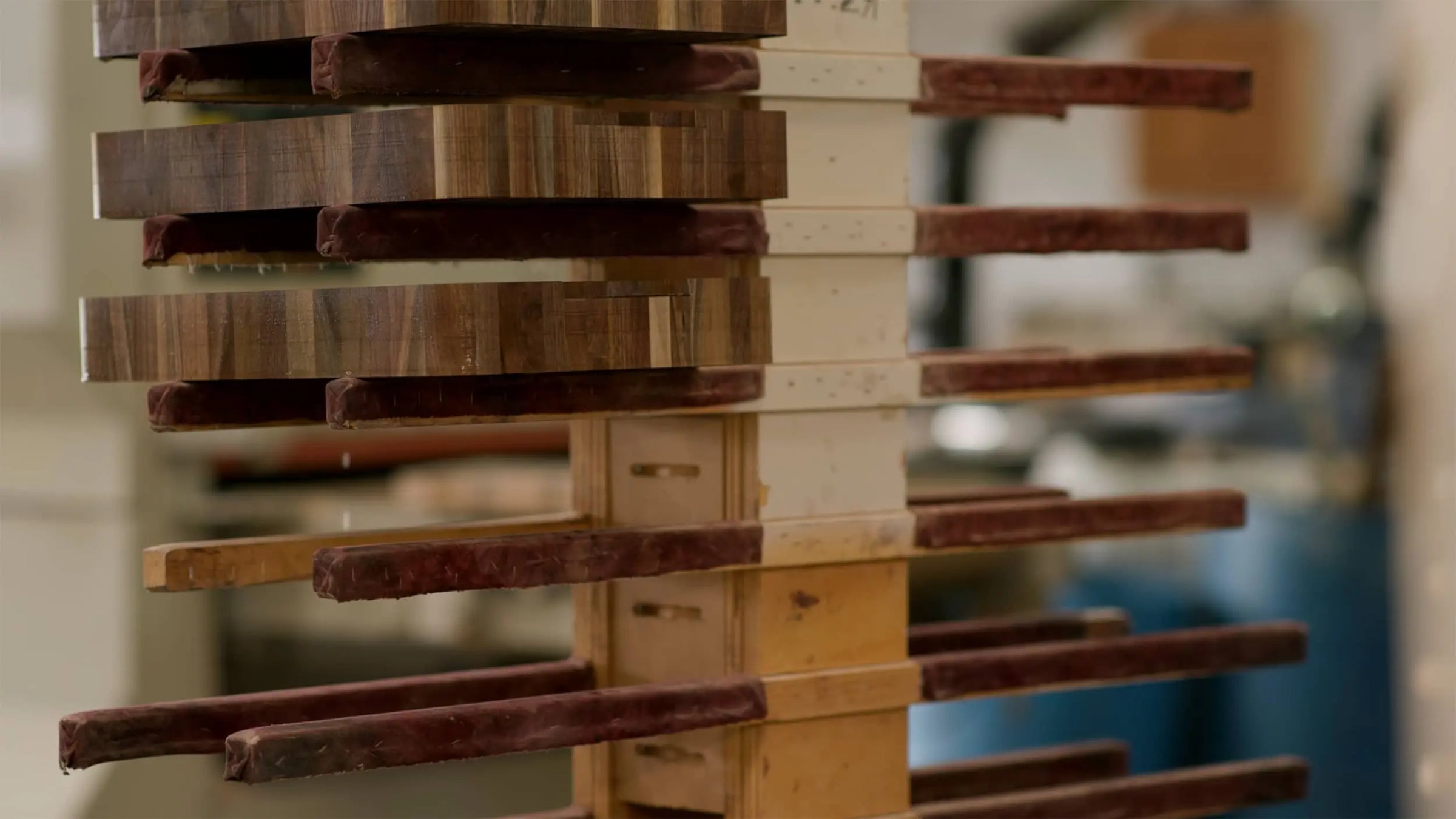Stacked end grain chopping blocks on a drying rack in a workshop, showcasing the detailed wood grain patterns and craftsmanship involved in their creation