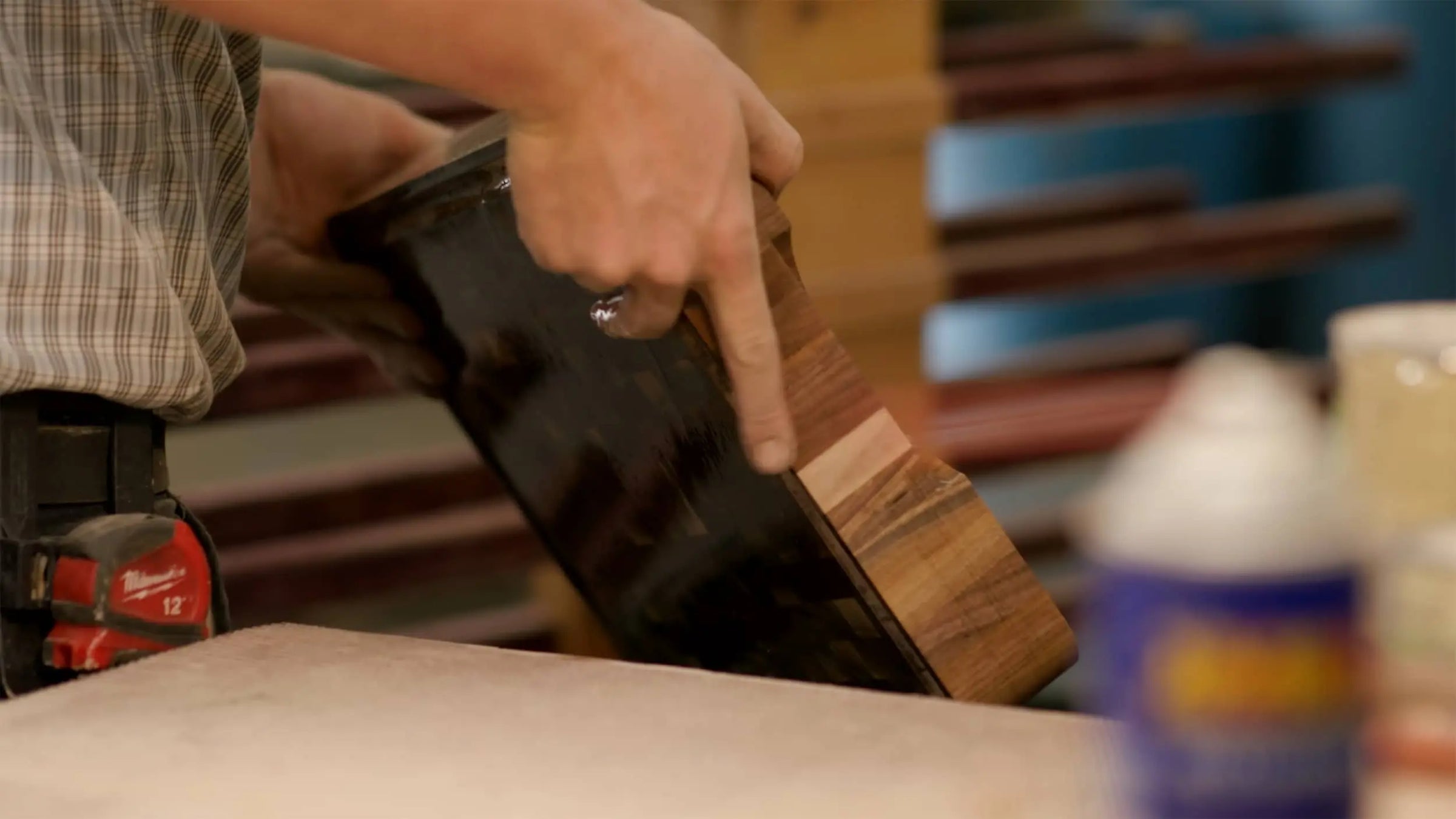 Close-up of a person holding a finished wooden end grain chopping block, demonstrating the smooth, polished surface and quality craftsmanship