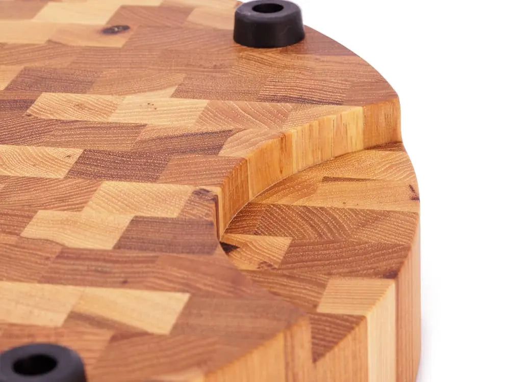 Close-up of a round hickory end grain butcher block with a groove and rubber feet
