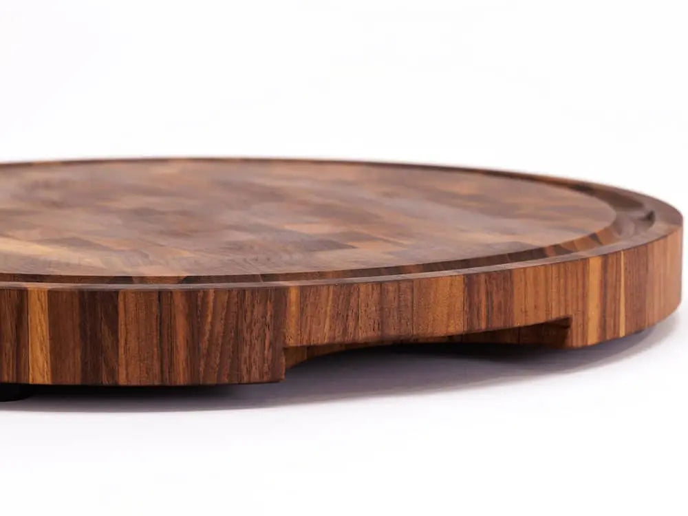 Side view of a round black walnut end-grain cutting board with a checkered pattern of various wood tones, featuring a smooth finish, against a white background