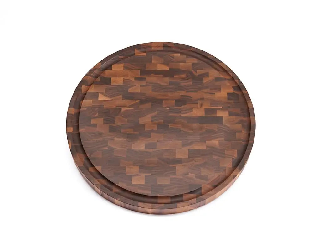 Top view of a round black walnut end-grain cutting board with a checkered pattern of various wood tones, featuring a smooth finish, against a white background