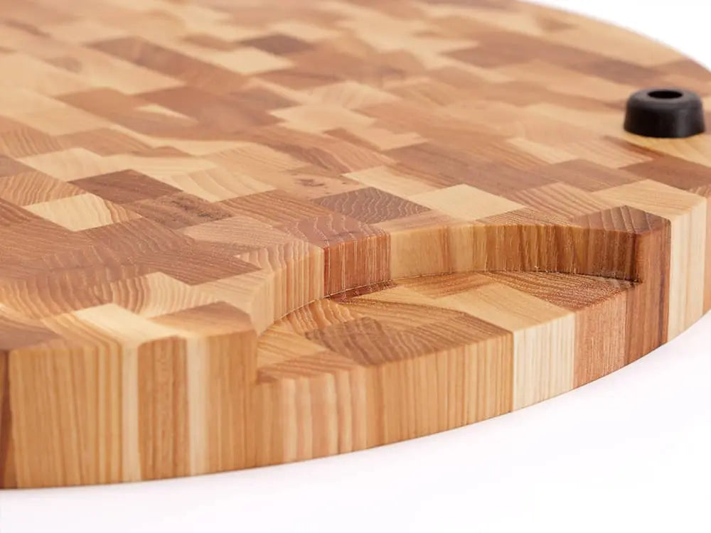 A close-up, bottom view of a round end grain cutting board with a checkered pattern, with a primary focus on the handle of the board