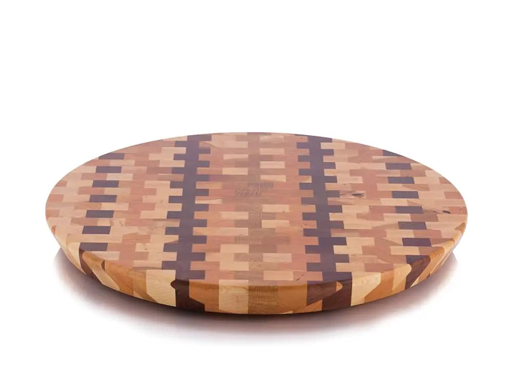 Top view of a round end-grain lazy susan with a geometric mosaic pattern featuring dark brown vertical stripes and lighter brown squares, on a white background