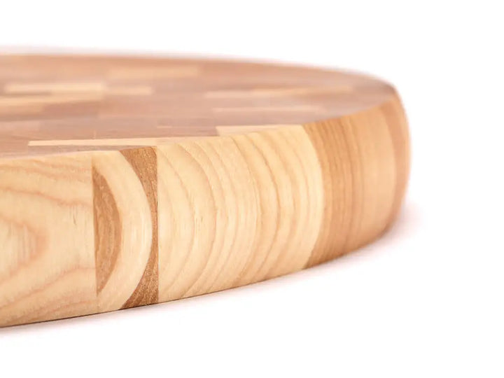 Close-up side view of an end-grain charcuterie board board with a checkered pattern of various wood tones, featuring a smooth finish, against a white background