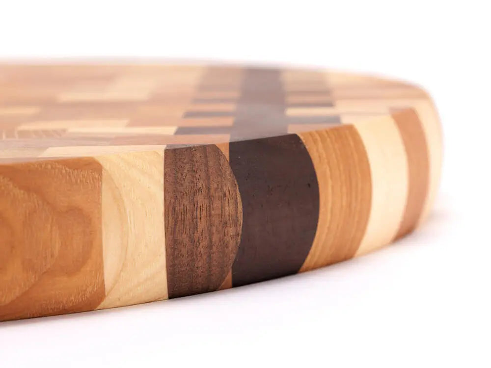 Close-up, side view of an end-grain charcuterie board board with a checkered pattern of various wood tones, featuring a smooth finish, against a white background
