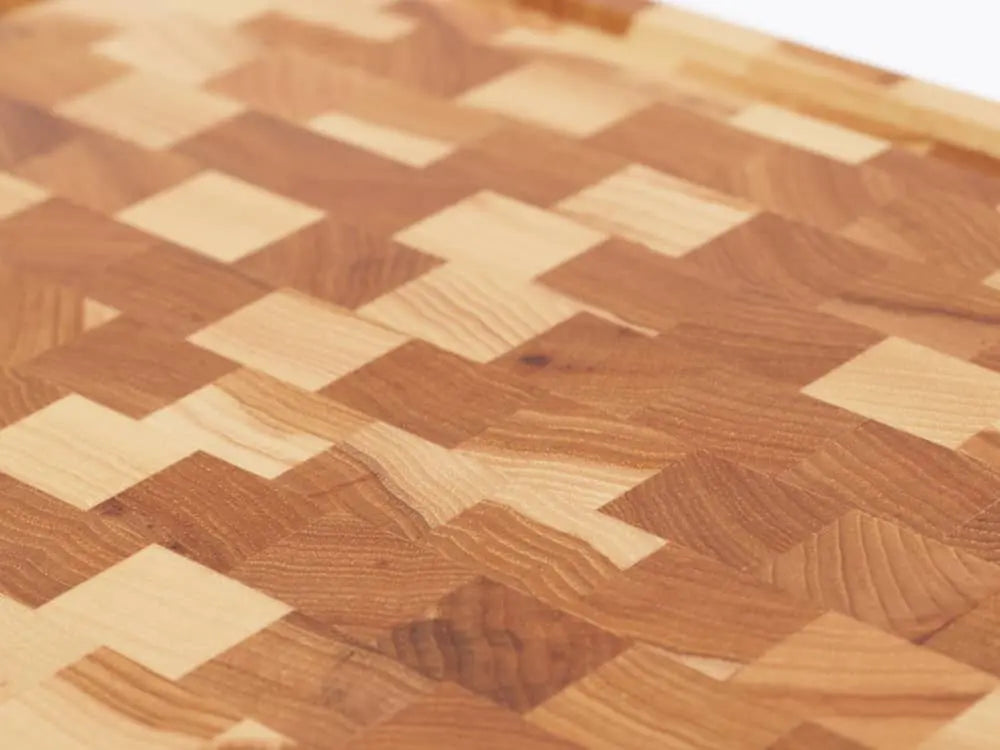 Close-up view of a Hickory Nut end-grain cutting board with a checkered pattern of various wood tones, showing the intricate grain and texture