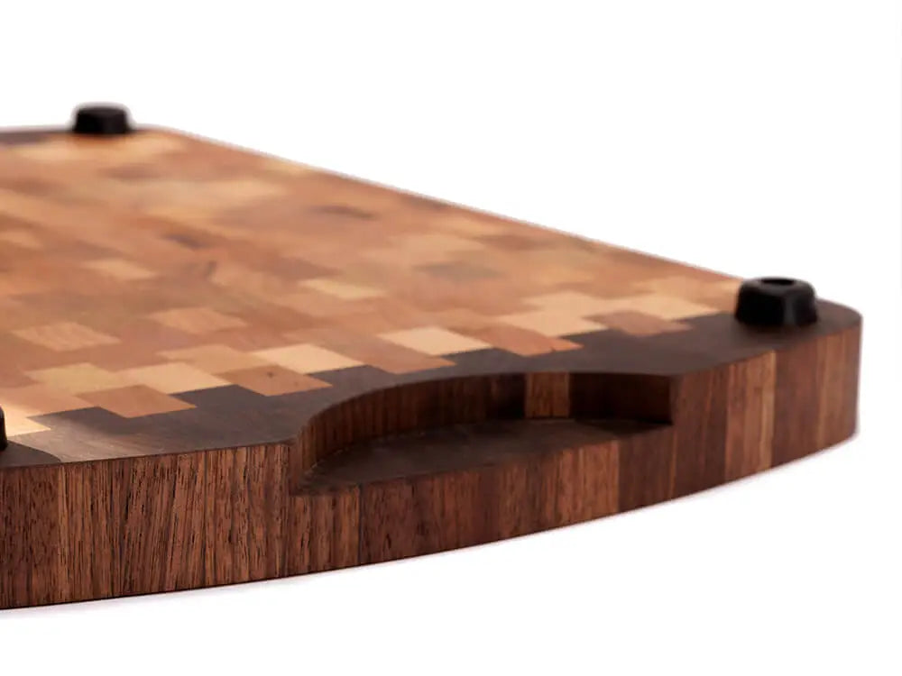 A close-up, bottom view of an end grain cutting board with a checkered pattern and rounded edges, with a focus on the handle of the board